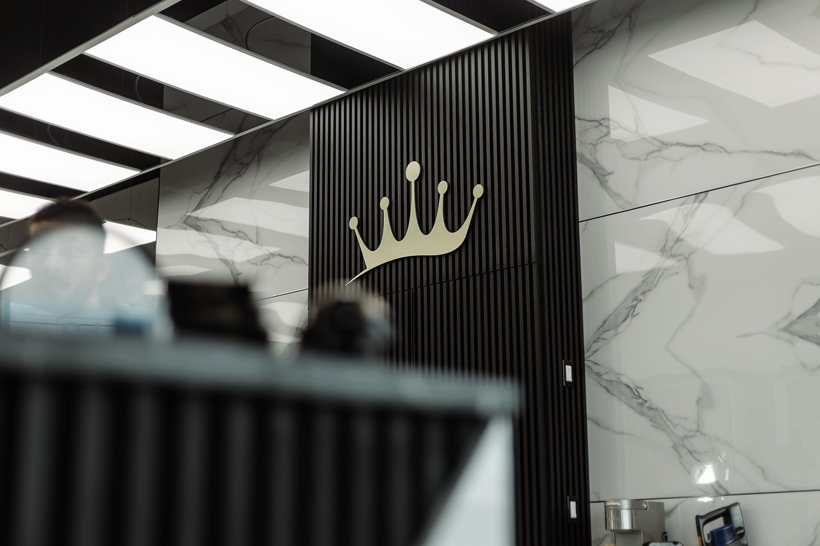 Ritz Barbershop crown logo mounted on dark ribbed paneling with marble walls